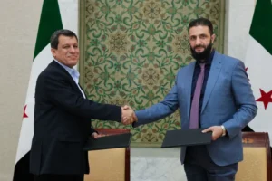 أحمد الشرع (يمين) يصافح مظلوم عبدي بعد توقيع اتفاق مارس/آذار (الفرنسية)