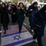 متظاهرون يسيرون على علمي أميركا وإسرائيل خلال تجمع سنوي احتفالا بذكرى الاستيلاء على السفارة الأميركية بطهران (أسوشيتد برس)