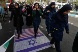 متظاهرون يسيرون على علمي أميركا وإسرائيل خلال تجمع سنوي احتفالا بذكرى الاستيلاء على السفارة الأميركية بطهران (أسوشيتد برس)