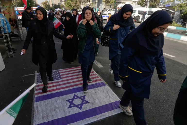 متظاهرون يسيرون على علمي أميركا وإسرائيل خلال تجمع سنوي احتفالا بذكرى الاستيلاء على السفارة الأميركية بطهران (أسوشيتد برس)