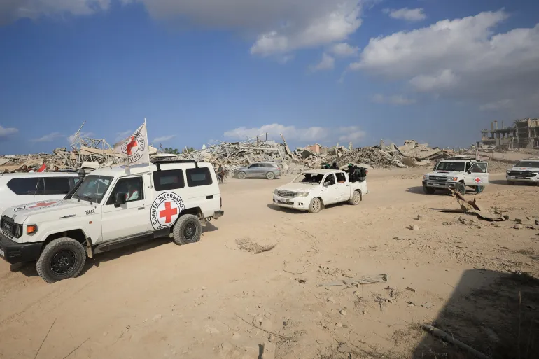 عناصر من الصليب الأحمر مع مقاتلين من كتائب القسام خلال التوجه نحو حي الزيتون للبحث عن جثث الأسرى (رويترز)